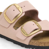 Pink sandal with gold buckles on a white background