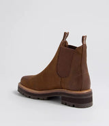 A brown suede Chelsea-style ankle boot with elastic side panels and a chunky lug sole, shown from a side-rear angle on a light gray background.