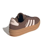 A single Adidas platform sneaker shown from a three-quarters rear angle on a white background. The shoe features a dark brown suede upper, white three-stripes detailing on the side, a cream heel tab with the Adidas logo, and a thick tan platform sole.