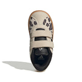A single Adidas toddler sneaker shown from a top-down view on a white background. The shoe features a light beige suede upper with black leopard print overlays, two hook-and-loop straps, a black collar, and a brown gum outsole.