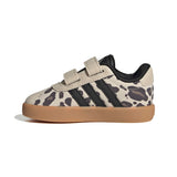 A low-top sneaker featuring a beige and black animal print pattern, black three-stripes, a beige hook-and-loop strap closure, and a gum brown sole, shown against a plain white background.