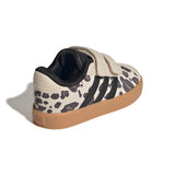 A single Adidas low-top sneaker shown from a three-quarters rear angle on a white background. The shoe features a cream suede upper with a black animal spot pattern, black three-stripes, a black hook-and-loop strap closure, and a brown gum sole.