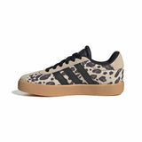 A single low-top sneaker shown in a side profile on a white background. The shoe features a beige and black animal print upper with black laces and three black stripes, and a gum-colored sole.