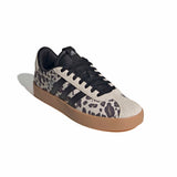 A low-top Adidas sneaker featuring a beige and black leopard print pattern on the side panels, black laces, a black heel tab, and a brown gum sole, shown on a white background with a soft shadow.