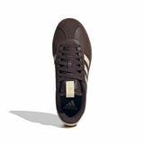 Dark brown Adidas sneaker with white stripes on a white background