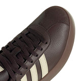 Dark brown sneaker with white stripes on a white background