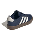 A navy blue Adidas sneaker shown from a three-quarters rear angle, featuring white three-stripes on the side, a white heel tab, and a brown rubber sole, set against a plain white background.