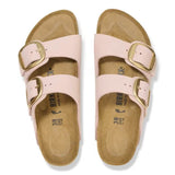 Pair of pink sandals with gold buckles on a white background