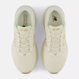 A pair of New Balance 680 running shoes in cream with metallic gold accents, shown from a top-down view on a light gray background.